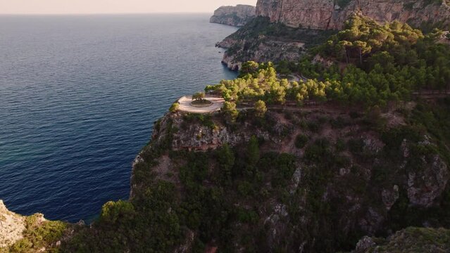 Aerial view of a roundabout on top of a cliff close to shoreline at sunset, Cala Moraig, Zona Encinas, Cumbre del Sol, Alicante, Spain