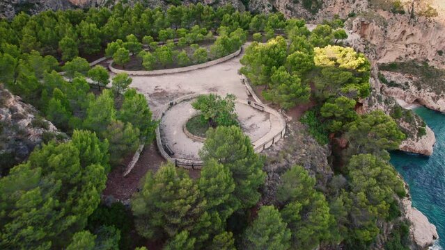 Aerial view of a roundabout on top of a cliff close to shoreline at sunset, Cala Moraig, Zona Encinas, Cumbre del Sol, Alicante, Spain