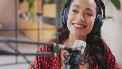 Beautiful radio host speaking on mic while recording podcast in studio. Young mixed race woman recording a podcast in studio. Joyful multiethnic woman speaking on microphone at her home studio. - Powered by Adobe