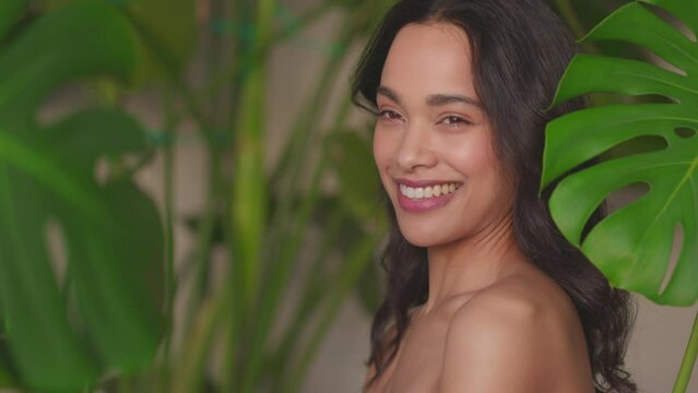 Beauty natural woman with monstera leaf looking at camera