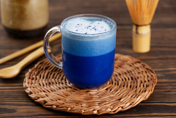 Blue matcha latte tea made from clitoria flowers with coconut milk on a brown table. Healthy drink, lactose, gluten and sugar free.
