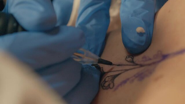 Slow motion shot of a tattoo artist tattooing a client with flowers