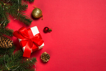 Christmas background with present, fir tree and decorations at red background. Top view with space for your text.
