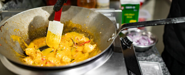Professional chef cooking chicken curry food in wok pan on kitchen