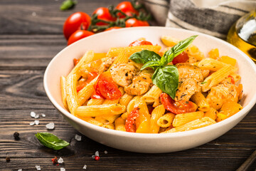Pasta with chicken and vegetables at wooden table. Traditional italian food.
