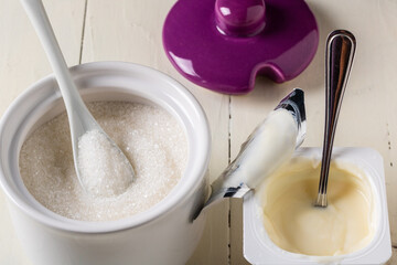 An open package of yogurt and sugar in a ceramic container on the table