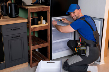 An electrical technician working on the repair of a refrigerator or refrigeration equipment. 