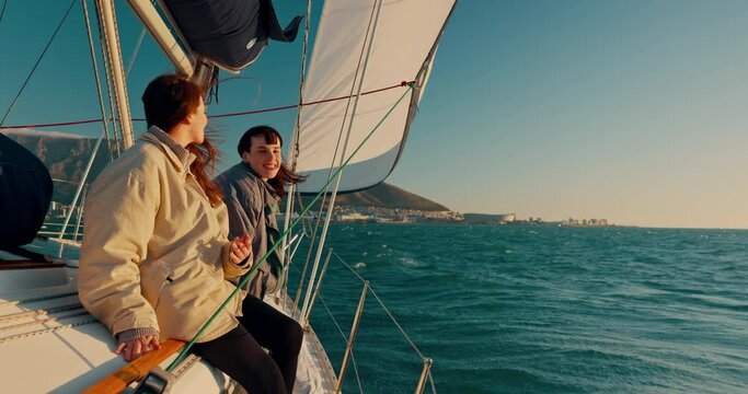 Sailing, boat and friends at sea for adventure together as love, happiness and travel on sunset island location. Wind, yacht and happy people with freedom on a cruise for luxury ocean holiday