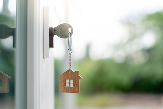 Landlord key for unlocking house is plugged into the door. Second hand house for rent and sale. keychain is blowing in the wind. mortgage for new home, buy, sell, renovate, investment, owner, estate