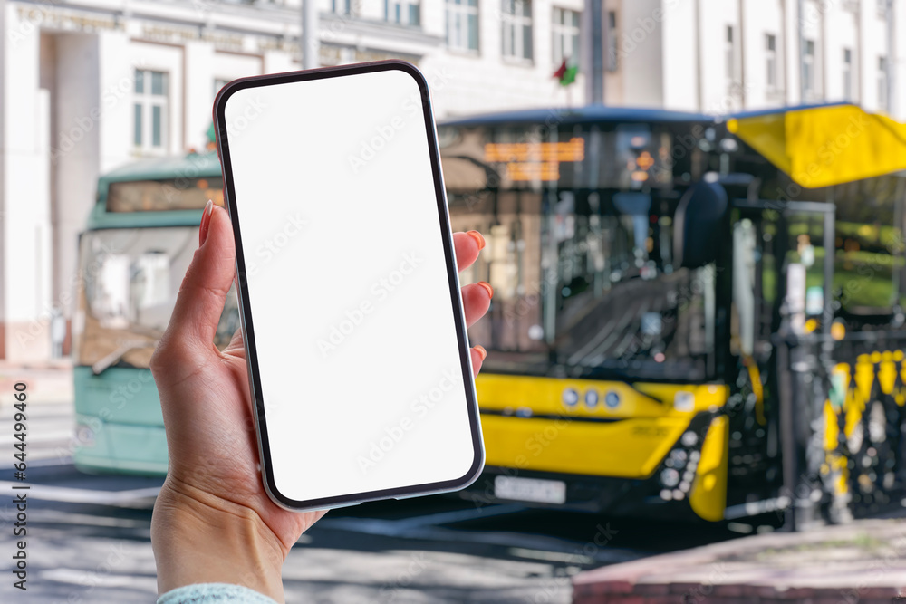 Poster girl holds a mock-up of a smartphone with a white screen in her hands at a bus stop against the back