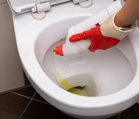 Woman in red rubber gloves cleaning toilet. close up hands women wearing protect glove red using liquid cleaning solution cleaning flush toilet, disinfection and hygiene concept