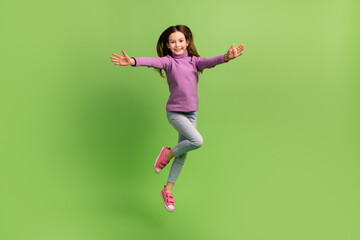 Fototapeta na wymiar Full body cadre of funky schoolkid little girl jump active free time peaceful friendly greetings cuddles isolated on green color background