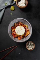 A top view of a grey bowl filled with Chinese-style seafood rice, presented on a black background with chopsticks and sesame seeds scattered around the table