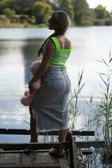 Portrait of a girl on the river bank with a pink teddy bear