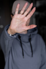 Close-up focus on a woman showing a stop gesture to the camera, blurred background, a strong young woman protesting against domestic violence and abuse, bullying, saying no to gender discrimination