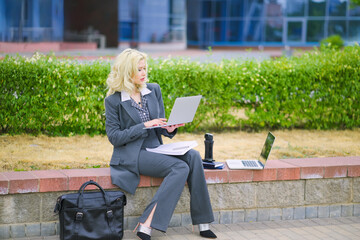 Business woman in an office suit working outside with a laptop computer