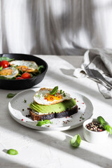 Toasted bread with avocado and fried egg for breakfast