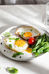 Plate with two fried eggs and greens for breakfast