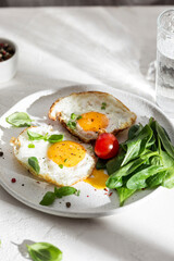 Plate with two fried eggs and greens for breakfast