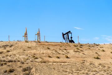 Oil wells at the top of a desert hillin California  on a clear autumn day