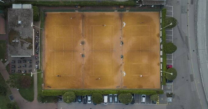 Aerial view of people playing tennis in a tennis club court along Lugano lake, Melide, Ticino, Switzerland.