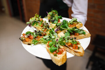 Catering food at the party. Catering service. The waiter holds a plate of appetizers, with...
