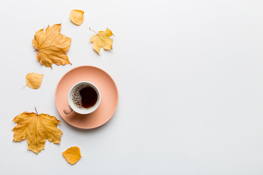 Flat lay composition with colorful Autumn cup of coffee and leaves on a color background. top view