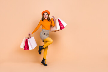 Full size photo of funny overjoyed girl hold packages empty space isolated on beige color background