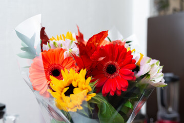 Colorful bouquet of gerberas and sunflowers in a transparent film for bouquets