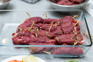 Raw beef meat rolls with spices and herbs in a glass tray on the table