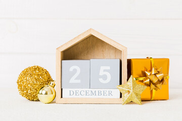 25 december. Christmas composition on colored background with a wooden calendar, with a gift box, toys, bauble copy space