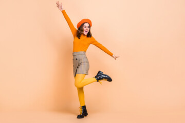 Full body portrait of overjoyed cheerful lady chilling dancing isolated on beige color background