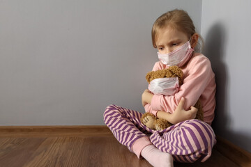 A cute girl is in a medical mask and hugs a toy. Concept: care for the health of loved one's,...