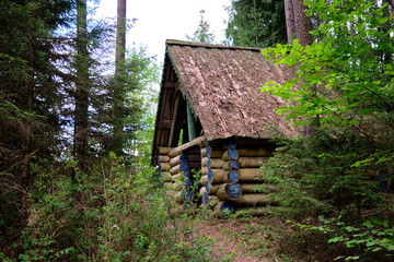 Horizontal photo of a part of a wooden house in a green forest.