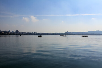 A silhouette island and boat sailing on the calm sea at sunset in the background of mountains. Beautiful sky. For travel, background and blog etc. concepts. West Lake. Hangzhou city China