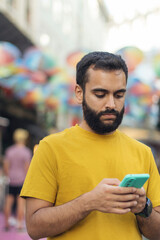 Retrato de hombre joven con barba mirando su teléfono móvil