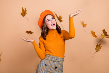 Photo of joyful glad adorable lady catching dry dropping leaves have fun good mood enjoy nice weather isolated on beige color background
