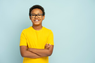 Portrait of smiling African American boy in yellow casual t shirt wearing glasses with crossed arms