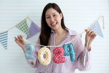Asian woman holding mobile numbers 2024 are made from beautifully printed fabric on white...