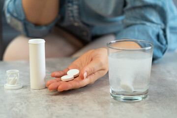 Womens hands with pills and water glass with effervescent tablet. Soluble drug.Take medicine