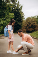 little girl is going to school. Dad ties his daughter's shoes