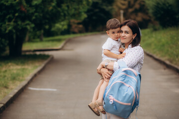 Child going back to school. Mother and kid getting ready for first school day after vacation. Little boy and mom going to kindergarten or preschool. Student packing books, apple and lunch in backpack.