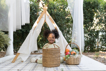 African American little girl playing alone with fruits in basket in the garden