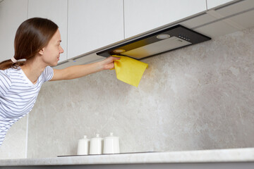 Housework and cleaning service concept. Woman hand cleaning range hood in the kitchen with a rag or...