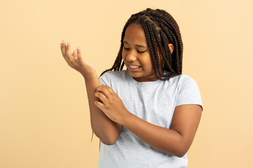 Sad attractive African American girl holding hand, scratch, wound isolated on beige background