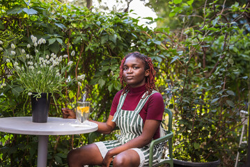 Portrait of a black non-binary person sitting in an outdoor cafe
