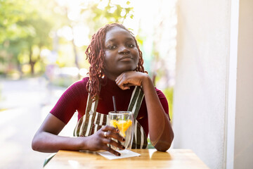 Portrait of a black non-binary person sitting in an outdoor cafe
