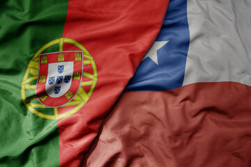 big waving national colorful flag of portugal and national flag of chile .