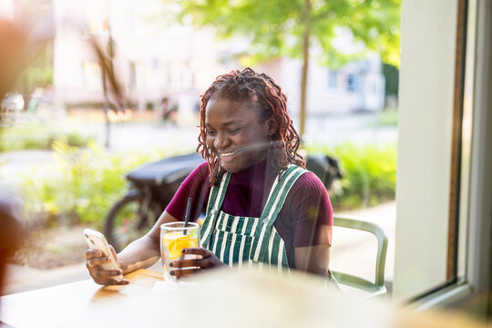 Portrait of a black non-binary person sitting in an outdoor cafe
