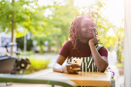 Portrait of a black non-binary person sitting in an outdoor cafe
